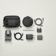 Travel tech flat lay with cable organizer bag, compact charger, foldable charging stand, tech pouch, and charging cables.