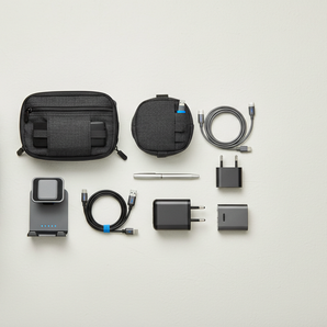 Travel tech flat lay with cable organizer bag, compact charger, foldable charging stand, tech pouch, and charging cables.