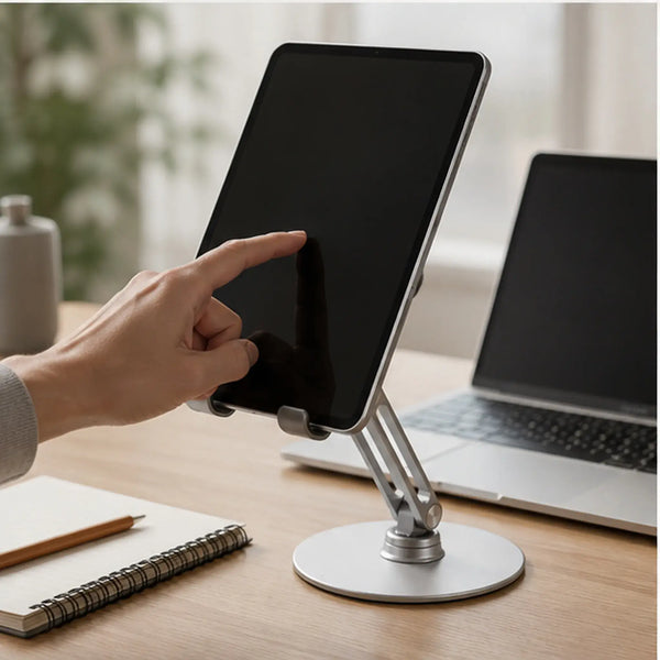 Person using a tablet on the 360° adjustable phone and tablet stand beside a laptop