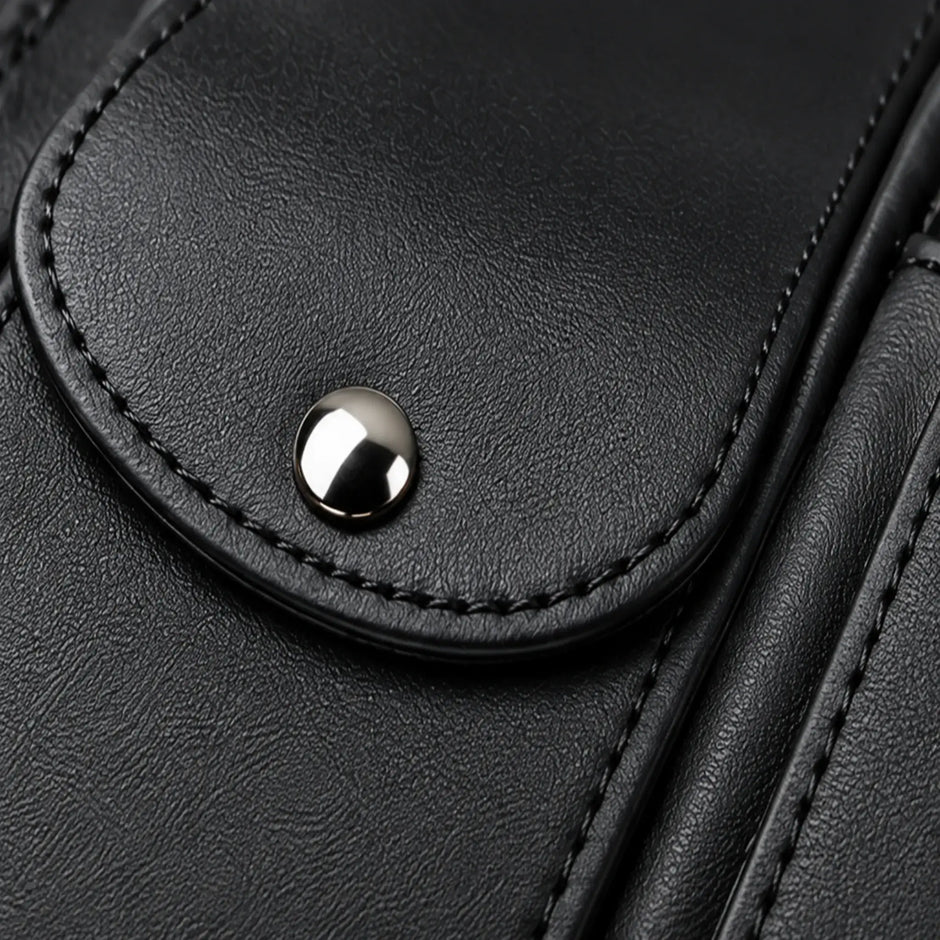 Close-up of black faux-leather texture, clean stitching, rounded piping, and metal snap closure